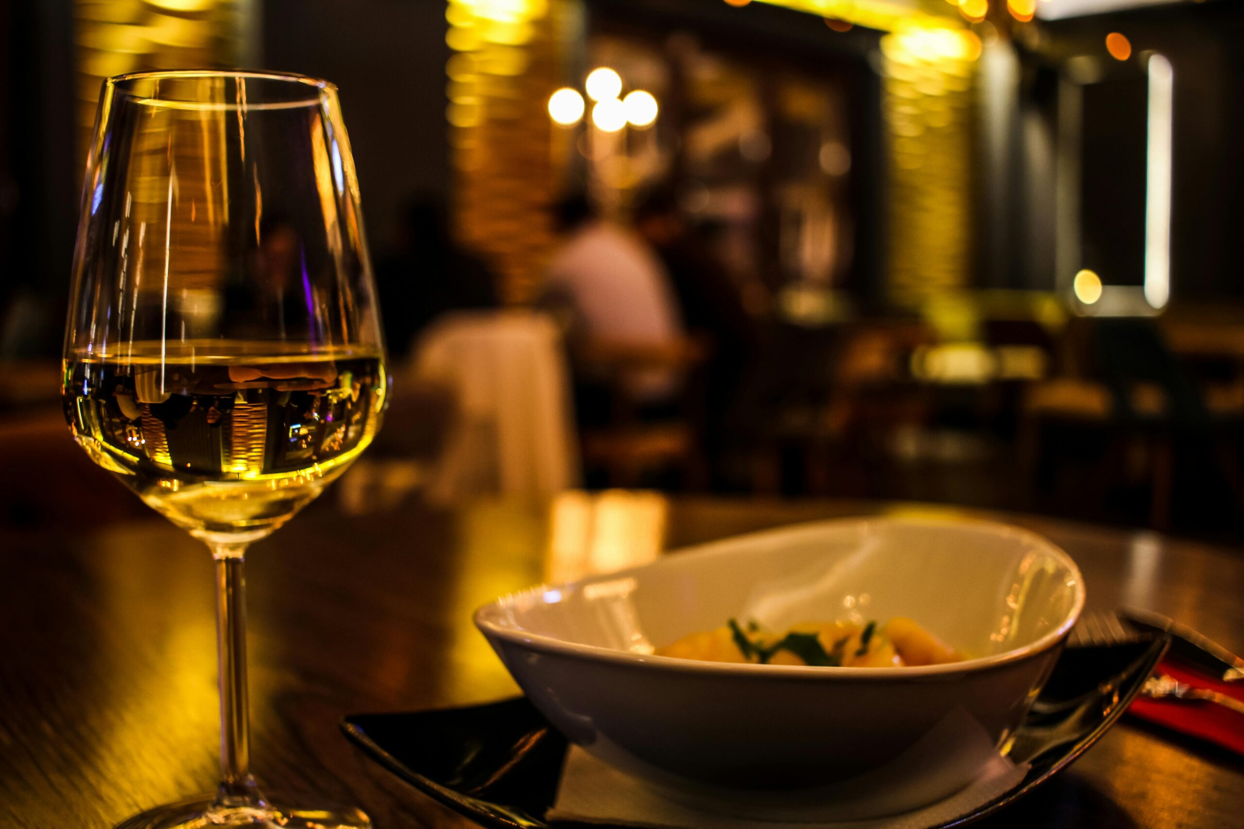 A classy dining setup featuring a glass of white wine in a cozy restaurant setting.